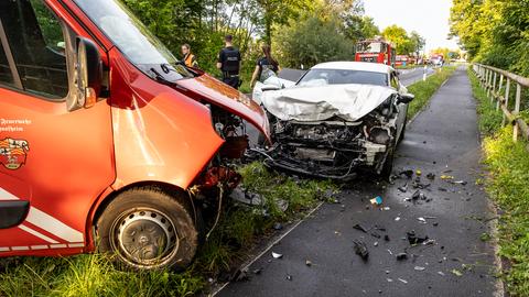 Das Bild zeigt ein rotes Feuerwehrzeug und einen silbernen Pkw, die frontal zusammengeprallt sind. Die Fahrzeugfront ist jeweils stark beschädigt.