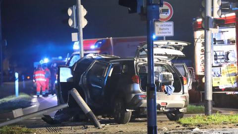 Demoliertes Auto an Ampelmast, im Hintergrund Rettungskräfte