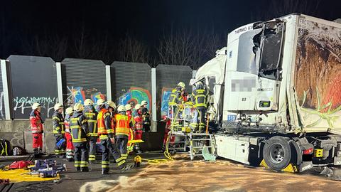 Front eines zerstörten Lastwagens, davor viele Einsatzkräfte, im Vordergrund eine mit Sand abgestreute Ölspur