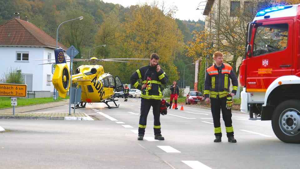 Einsatzkräfte und ein Rettungshubschrauber stehen an der Unfallstelle in Mossautal