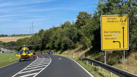 Gelber Rettungshubschrauber auf einer Bundesstraße. Daneben steht ein Verkehrsschild.