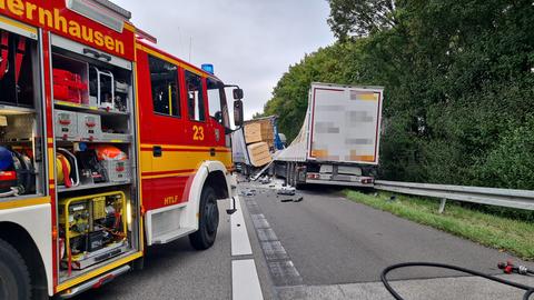 Feuerwehrwagen auf der Autobahn, daneben zwei ineinander gefahrene Lastwagen, einer hat Ladung verloren