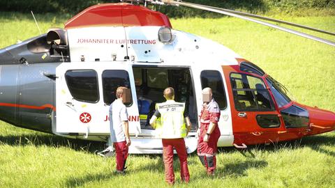 Rettungskräfte stehen auf einer Wiese vor dem Rettungshelikopter