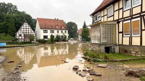 Mit braunem Wasser überflutete Fläche zwischen Wohnhäusern.