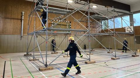 Einsatzkräfte des THW bauen ein Gerüst in der einsturzfgefährdeten Sporthalle auf, um das Dach zu stützen.