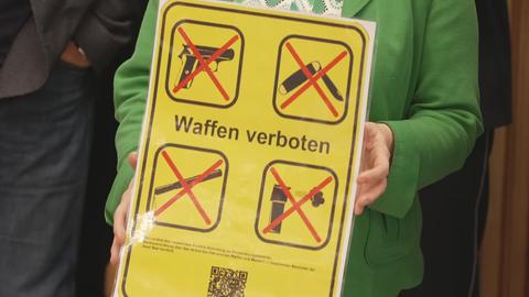 "Waffen verboten" steht auf einem Schild. Abgebildet sind eine Pistole, ein Messer und weitere Gegenstände.