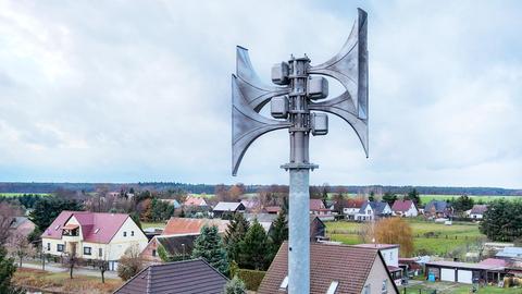 Nahaufnahme einer Sirene auf einem Dach. Unten/hinten klein Häuser eines Dorfes und die umgebende Landschaft plus Himmel.