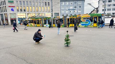 Mann fotografiert Mini-Weihnachtsbaum auf Kasseler Königsplatz