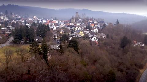 Foto eines kleinen Ortes (aus der Ferne), der inmitten von Wald und Landschaft liegt.