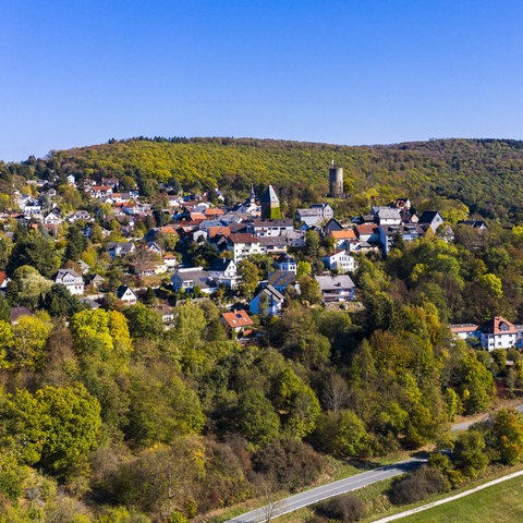 Foto eines kleinen Ortes (aus der Ferne), der inmitten von Wald und Landschaft liegt.