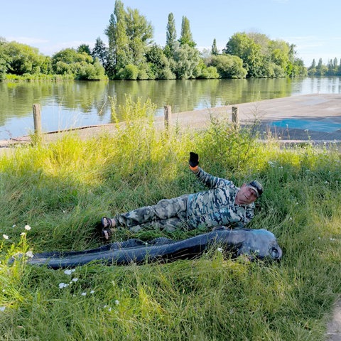 Wels liegt auf Gras, dahinter der Angler