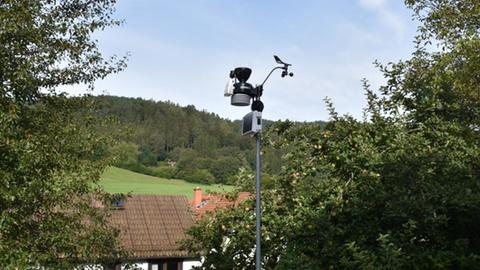 Wetterstation auf einem Mast, im Hintergrund hügelige Landschaft