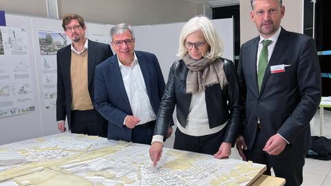 Wiesbadens OB Gert-Uwe Mende (2.v.l.), Bundesarchitektenkammer-Präsidentin Andrea Gebhard (M.) und andere Entscheidungsträger vor dem Plan des neuen Stadtteils