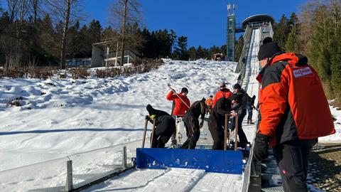 Menschen mit Schneeschaufeln an der Schanze