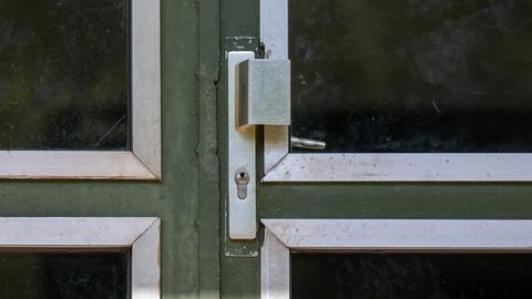 Handknauf und Schloss einer metallenen Eingangstür zu einem Mietshaus