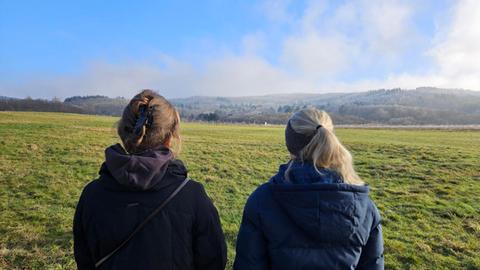 zwei Frauen von hinten vor Wiese und Wald