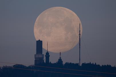 Gebäude auf dem Feldberg sind als Silhuette vor dem Vollmond zu erkennen, der wie ein riesiger Ballon erscheint.