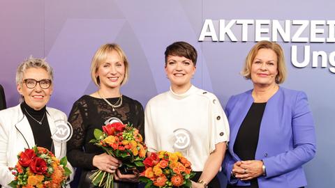 Drei Preisträgerinnen mit Blumenstrauß neben Bundesinnenministerin Nancy Faeser.