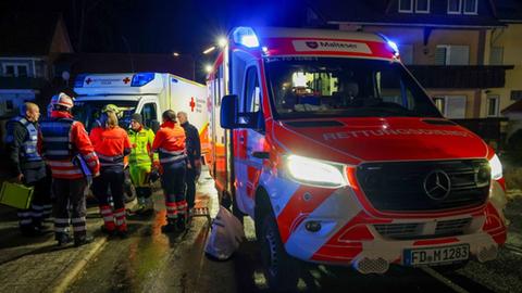 Rettungskräfte stehen in der Nacht vor Einsatzfahrzeugen.