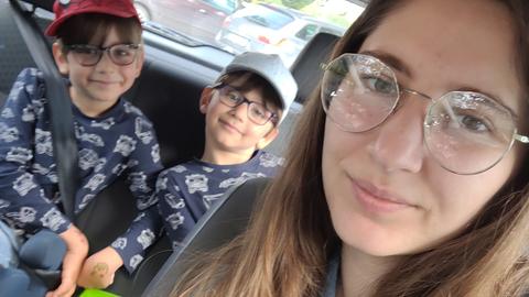 Mostafa und Yosof mit ihrer Mutter im Auto: die Kinder sitzen auf dem Rücksitz und grinsen in die Kamera. Alle drei tragen eine Brille.