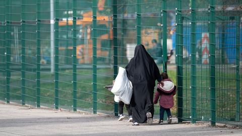 Eine Frau geht mit ihren Kinder über das Außengelände der Erstaufnahmeeinrichtung (HEAE) in Gießen. 