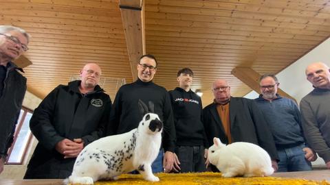 Zwei Kaninchen sitzen im Vordergrund, dahinter stehen der Politiker Bartol und Mitglieder des Kaninchenzüchtervereins