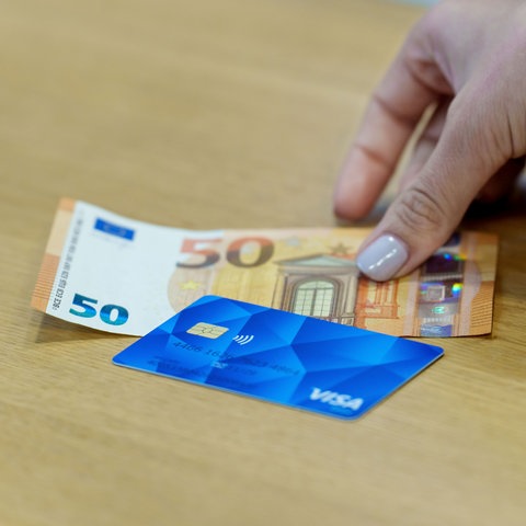 Die Bezahlkarte für Asylbewerber und ein 50 Euro Schein liegen nebeneinander. 