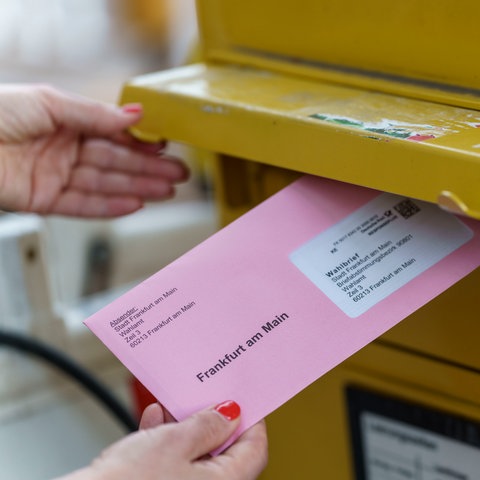 Eine Frau wirft ihre Briefwahlunterlagen zur Oberbürgermeisterwahl in Frankfurt in einen Briefkasten. 