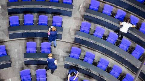 Von oben fotografierte vier Reinigungskräfte, die die Tische im Prenalrsaal des Bundestags abwischen