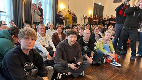 Menschen verfolgen eine Linken-Veranstaltung auf dem Boden sitzend.