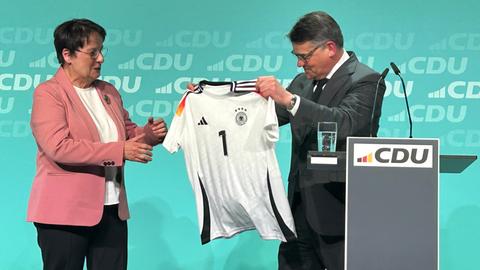 Ministerpräsident Rhein übergibt Patricia Lips ein Trikot mit der Aufschrift "1".