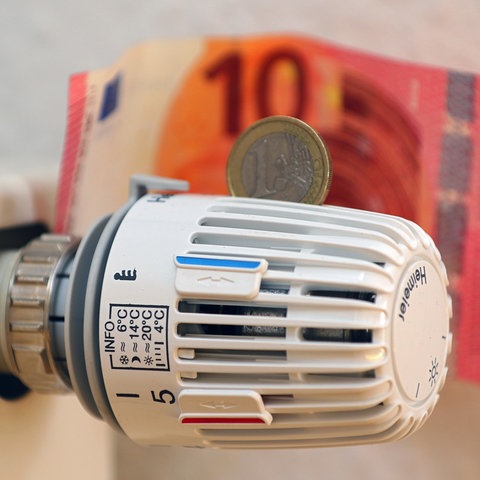 Das Thermostat eines Heizkörpers mit Geldscheinen und 1-Euro-Münze