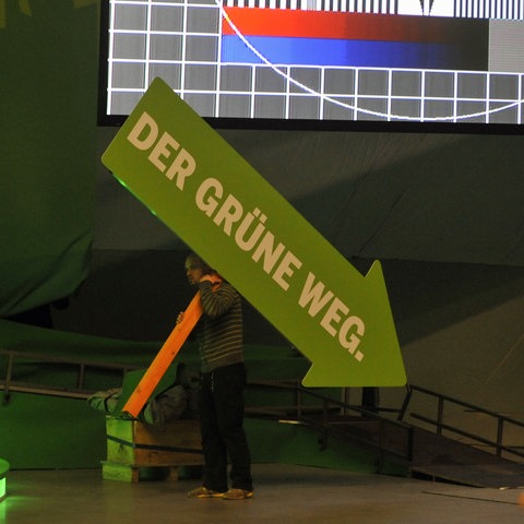 Ein grüner Pfeil auf einer Wahlveranstaltung zeigt nach unten.