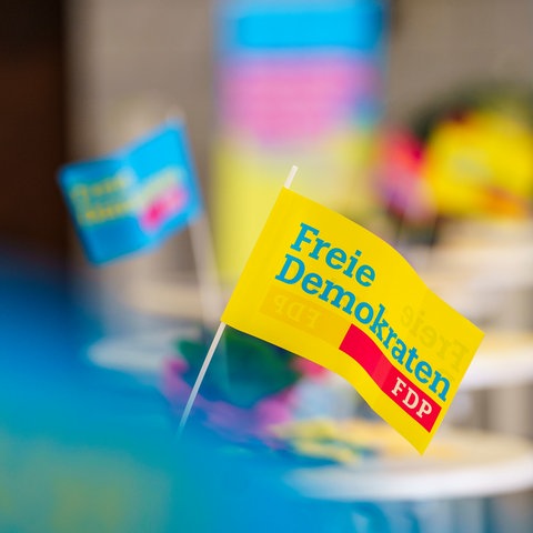 FDP-Fähnchen stehen an einem Wahlkampfstand.