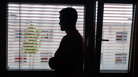 Ein Mann steht in der Unterkunft für Asylbewerber im Flughafenverfahren in Frankfurt vor einem Fenster und schaut hinaus. Man sieht von ihm nur seine Silhouette.