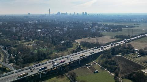 Luftaufnahme von nordwestlichen Stadtteilen von Frankfurt am Main und der A5 zwischen Westkreuz und Nordwestkreuz. Man sieht Äcker und Wiesen mit Bäumen, wo ein neuer Stadtteil gebaut werden soll. Im Hintergrund sind die Hochhäuser der Frankfurter Skyline zu sehen.