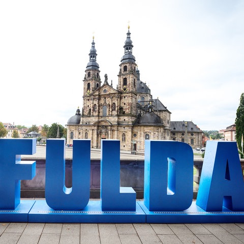 Ein Schriftzug Fulda in blau mit einem roten Herz vor dem Dom von Fulda