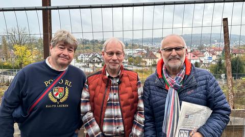 Drei älterere Herren stehen vor einem Bauzaun und einem Baugrundstück