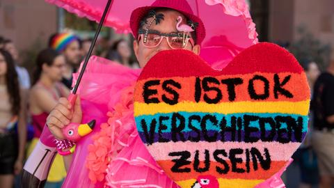 "Es ist ok, verschieden zu sein" steht auf dem selbst gebastelten Herzen eines in pink gekleideten Teilnehmers beim Christopher Street Day (CSD) Frankfurt unter dem Motto "Wir sind extrem Liebevoll".