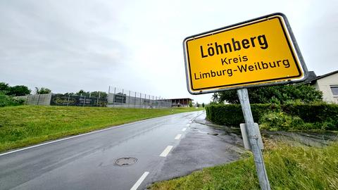 Ortsschild von Löhnberg im Vordergrund, im Hintergund eine Ortseinfahrt und einige Häuser