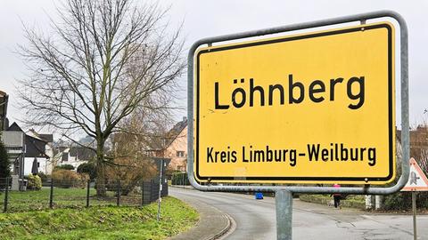 Ortsschild von Löhnberg im Vordergrund, im Hintergrund Straßen und einige Häuser