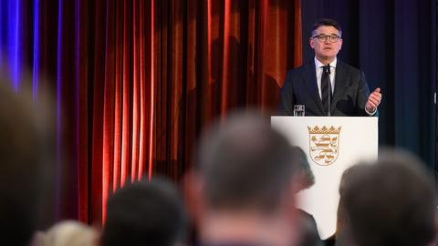 Boris Rhein (CDU), Hessischer Ministerpräsident, spricht bei einer Gedenkveranstaltung für die Opfer des Nationalsozialismus im Bürgerhaus der Stadt Bad Arolsen. Er steht hinter einem Pult mit dem Hessen-Wappen, vor ihm ein Mikrofon.