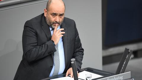 Omid Nouripour hält sich am Rednerpult des Bundestages den Zeigefinger vor den Mund