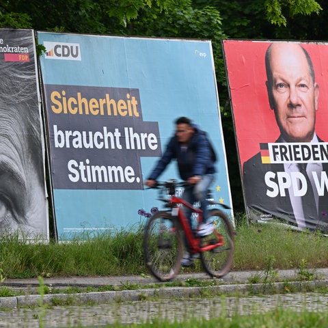 Ein Radfahrer fährt im Frankfurter Stadtteil Sachsenhausen an großen Plakaten von FDP (lr), CDU, SPD und Freien Wählern zur Europawahl vorbei 
