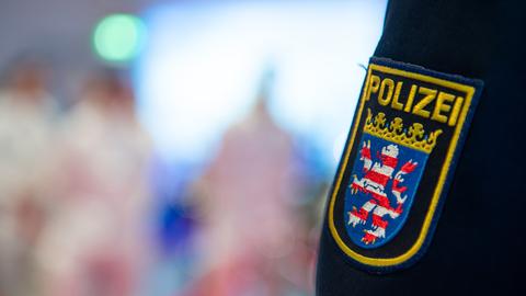 Das Wappen der Polizei Hessen auf einer Uniform des Präsidenten des Polizeipräsidiums Mittelhessen, dahinter unscharf Personen