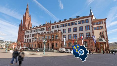 Außenansicht des Wiesbadener Rathauses. Auf dem Bild ein kleines "Label", bestehend aus einem Wahlkreuz, dem Wappen von Wiesbaden und dem Umriss der Stadt.