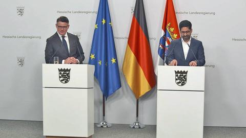 Ministerpräsident Boris Rhein (CDU, l.) und Wirtschaftsminister Kaweh Mansoori hinter Stepulten in der Staatskanzlei