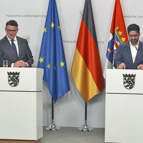 Ministerpräsident Boris Rhein (CDU, l.) und Wirtschaftsminister Kaweh Mansoori hinter Stepulten in der Staatskanzlei