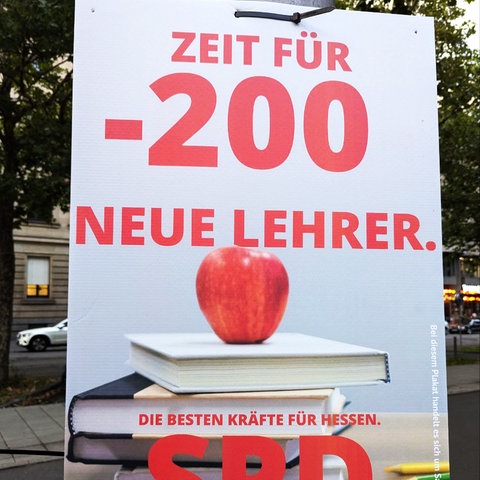 Plakat mit Büchern und einem roten Apfel, davor das Logo der SPD und Schrift in roter Farbe: "Zeit für -200 neue Lehrer"