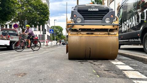 Ein Fahrradfahrer fährt durchs Bild, rechts steht eine Planierraupe.